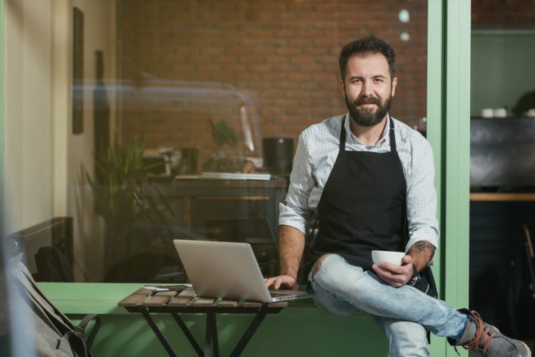 barista holding a cup and laptop