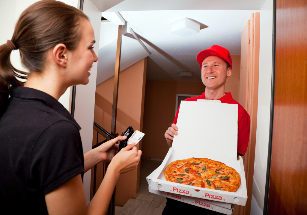 Man delivering pizza to a female customer