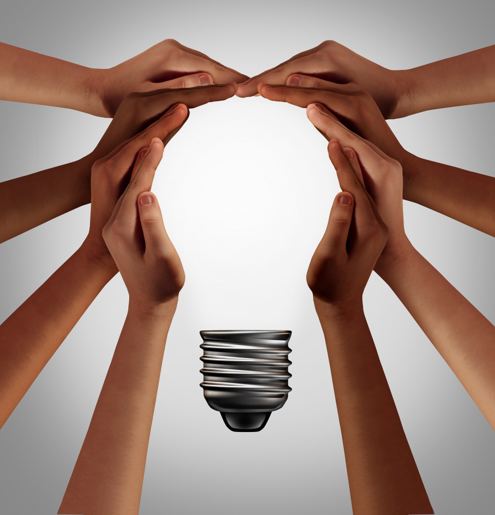 group of people holding hands to create a light bulb