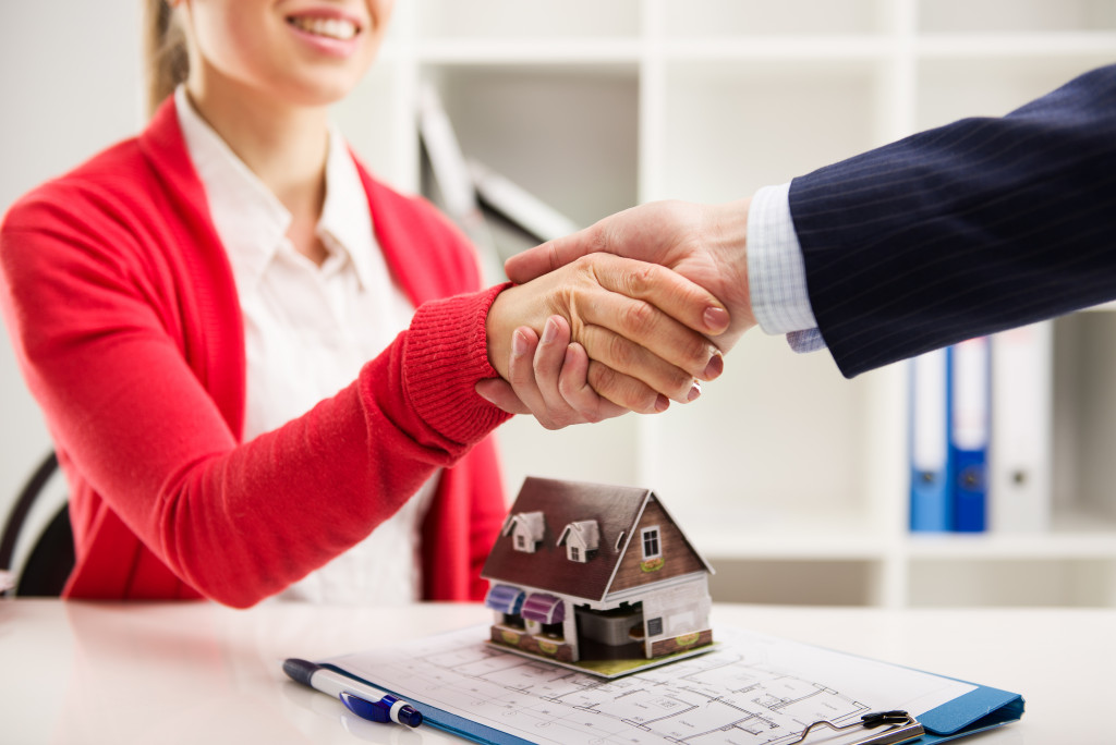 a woman shaking hands with an agent to represent a successful contract signing