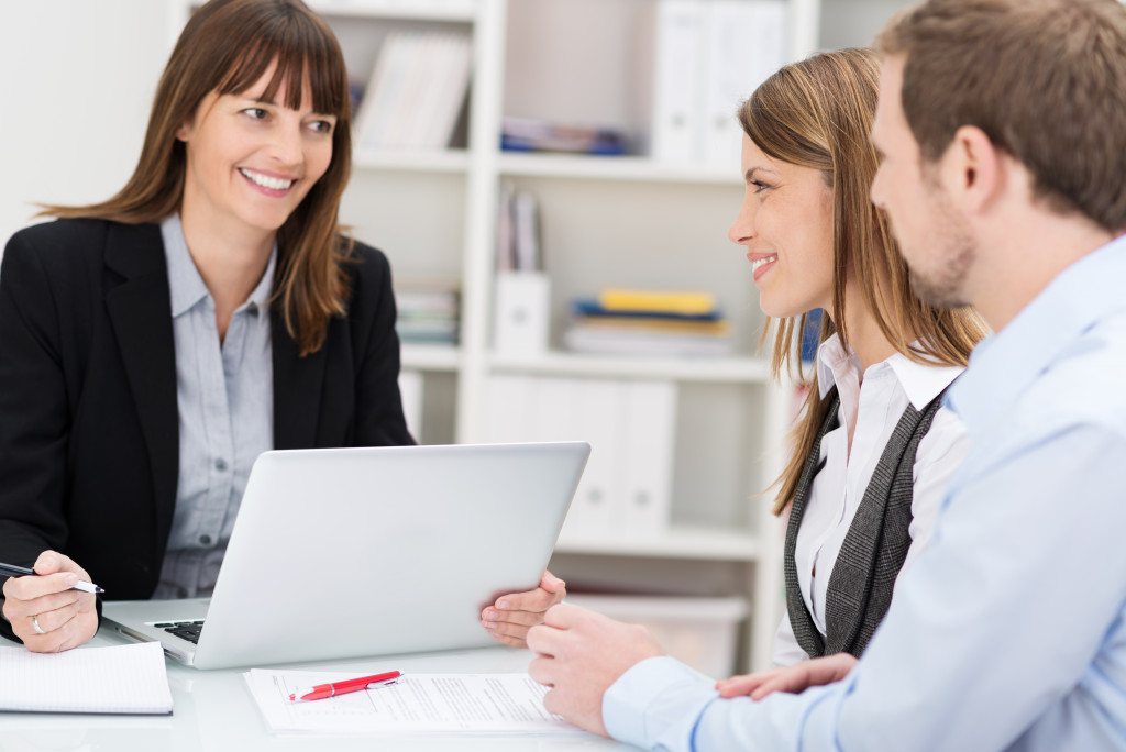 a female social worker talking to a couple while holding a laptop