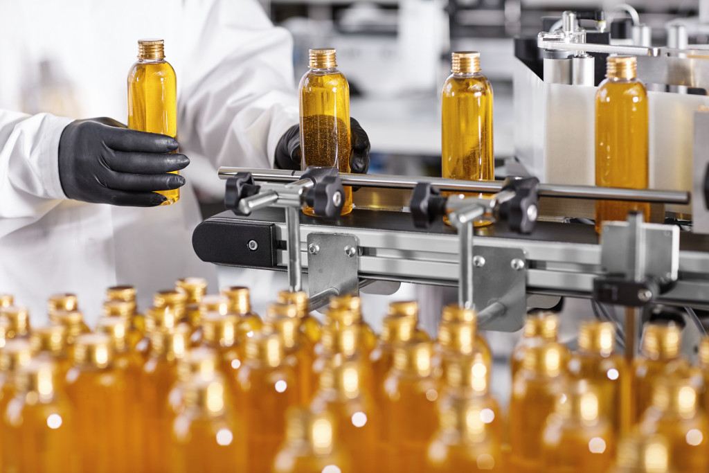 a worker holding amber bottles taking a sample batch from conveyor