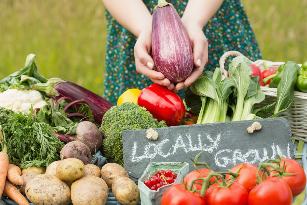 Female hands holding an eggplant above table of vegetables