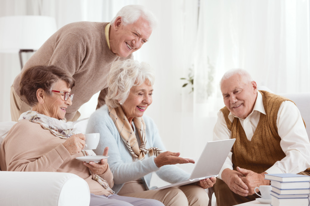 Four seniors using a laptop in a living room