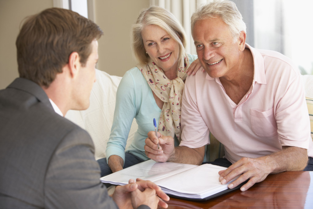 Senior couple signing a document with a financial advisor looking at them at home.