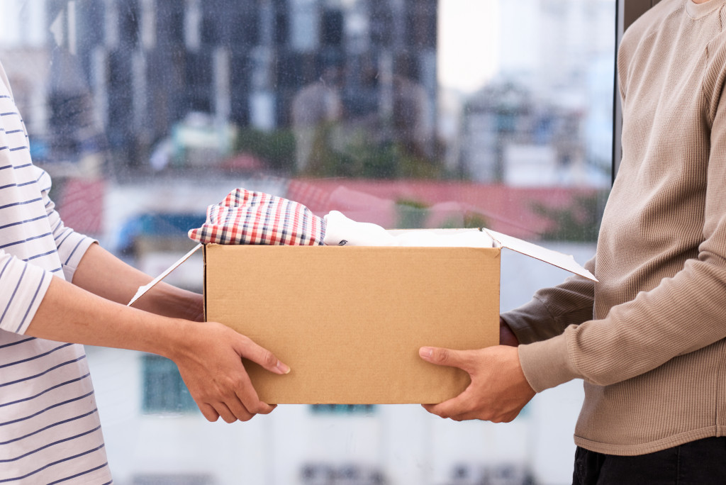 A woman handing out a box of clothes to a man as part of charity