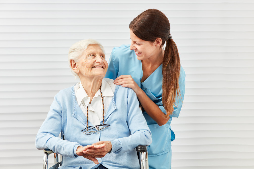 A nurse happily interacting with a senior woman on a wheelchair