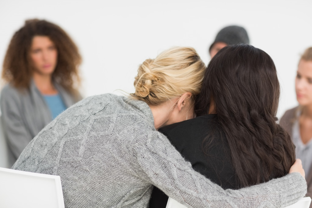 A woman embracing another woman in a group therapy session