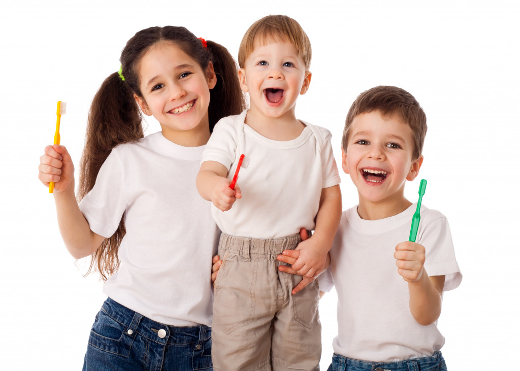 Three smiling children holding toothbrushes.