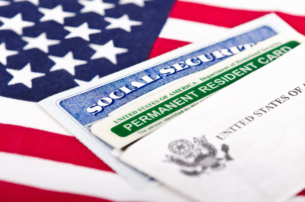 social security and permanent resident card on top of a US flag