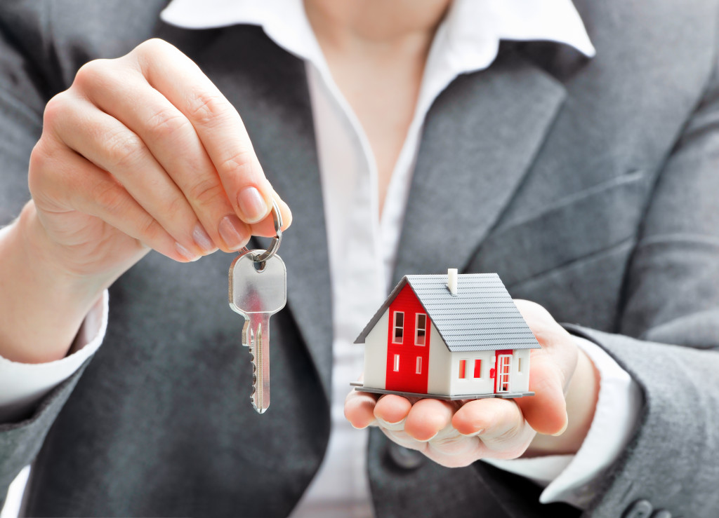 woman holding out a house key with a house model