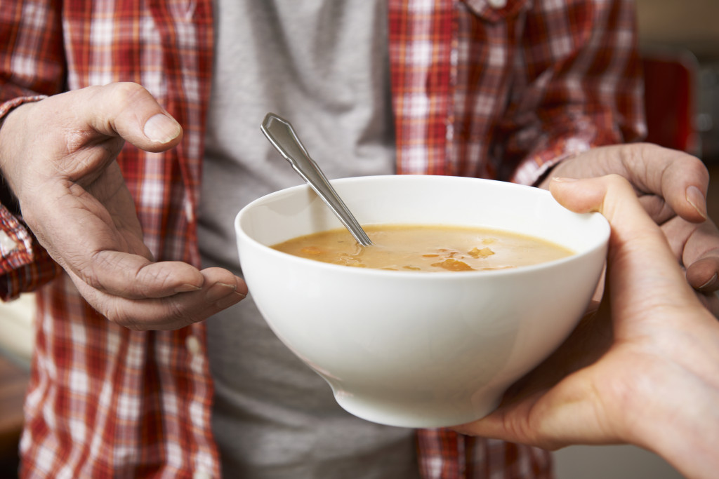 Handing a soup bowl to the needy