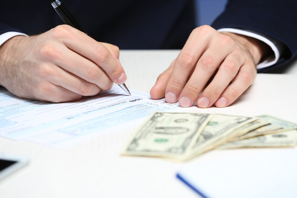 a man signing a document with money on the table