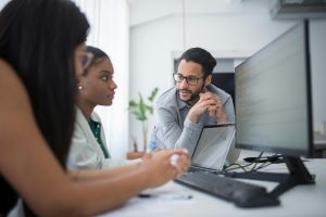 three employees collaborating at a desk in an office