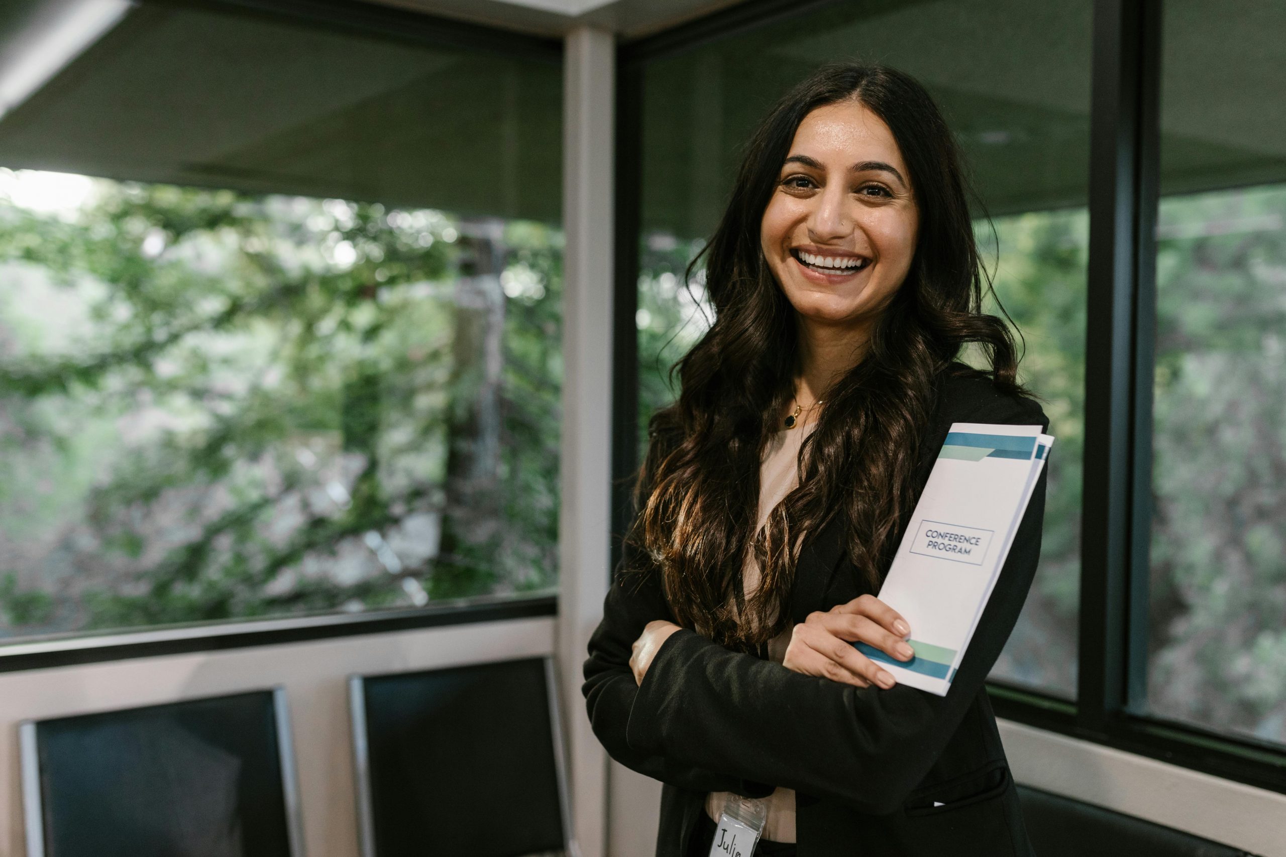 smiling woman in professional attire holding a program pamphlet