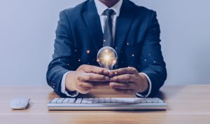 businessman holding a light bulb over a keyboard