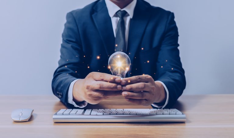 businessman holding a light bulb over a keyboard